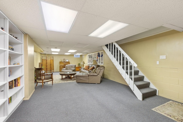 living room featuring carpet floors, concrete block wall, and stairs