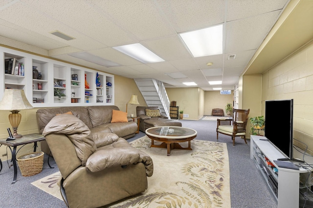 living room with carpet, visible vents, stairway, and concrete block wall