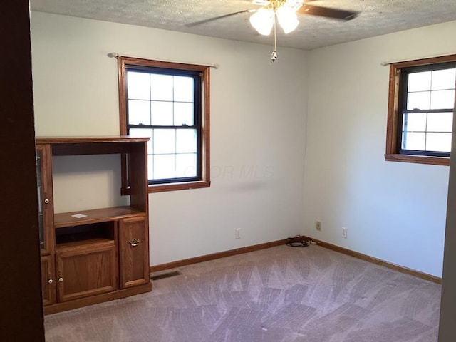 carpeted empty room featuring ceiling fan and a textured ceiling