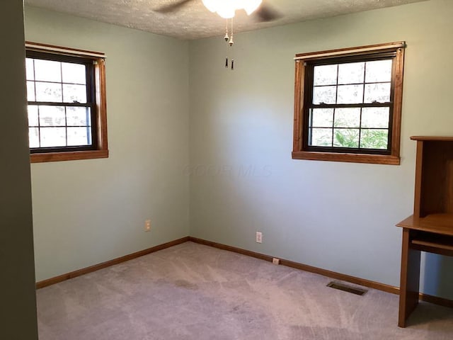 spare room featuring light carpet, ceiling fan, and a textured ceiling