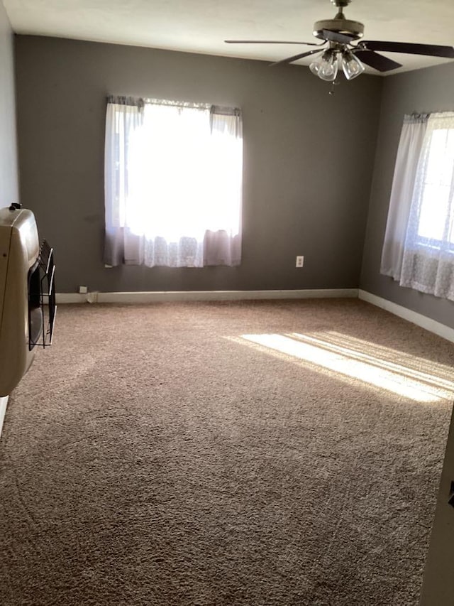 carpeted spare room with ceiling fan, a wealth of natural light, and heating unit