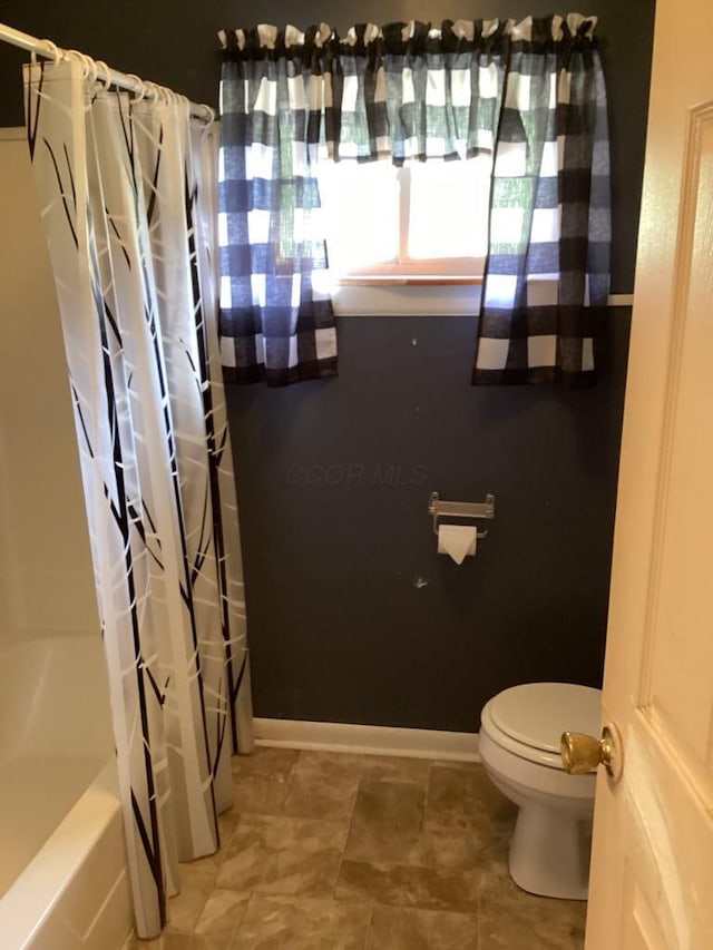 bathroom with toilet and shower / bath combo with shower curtain