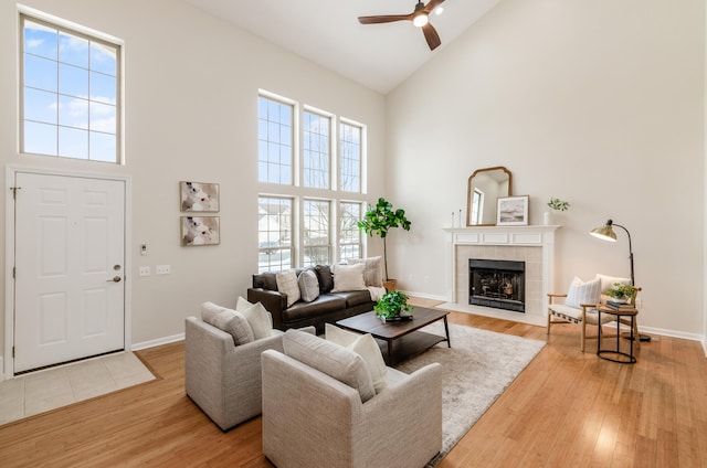 living room with high vaulted ceiling, a fireplace, ceiling fan, and light wood-type flooring