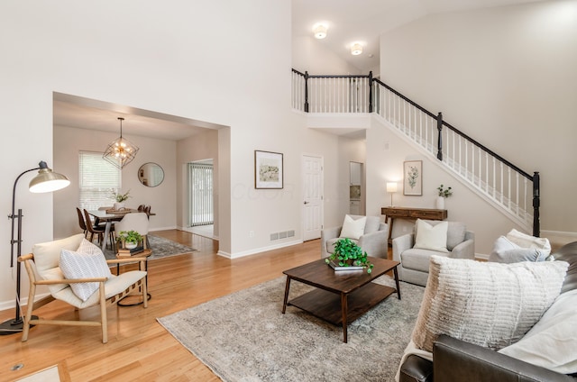 living room featuring high vaulted ceiling, hardwood / wood-style floors, and a notable chandelier