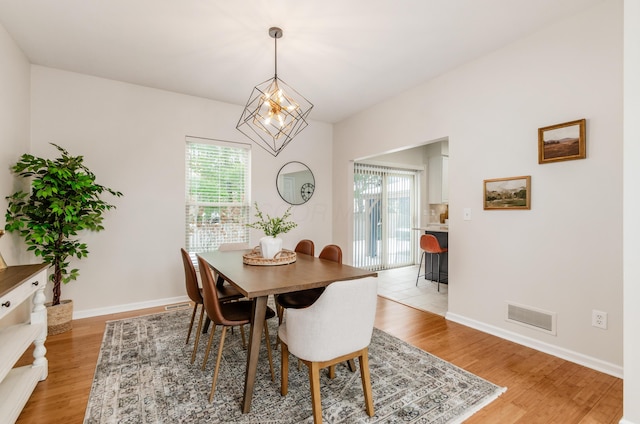 dining space with light wood-type flooring, an inviting chandelier, and a wealth of natural light