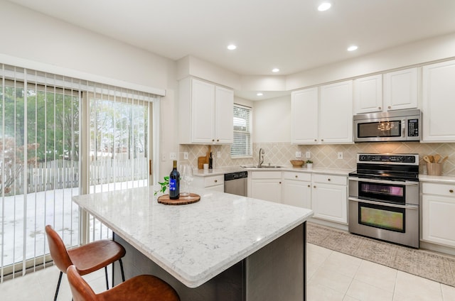 kitchen with light stone countertops, decorative backsplash, appliances with stainless steel finishes, and white cabinetry