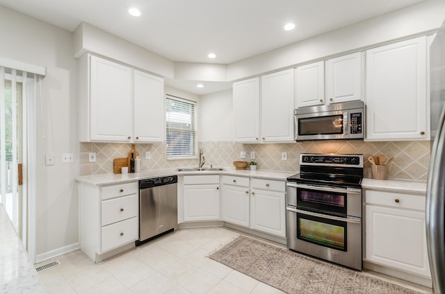 kitchen with light tile patterned flooring, sink, stainless steel appliances, and white cabinetry