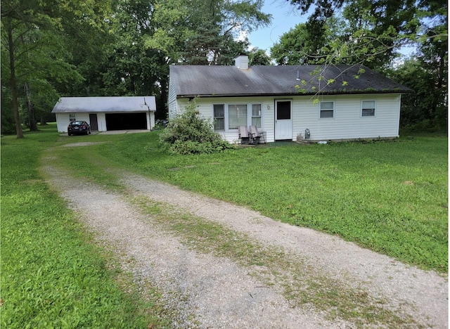 ranch-style home featuring a front yard, a garage, and an outbuilding