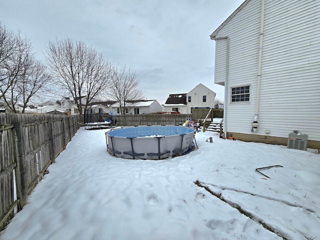 yard covered in snow featuring a fenced in pool and a trampoline