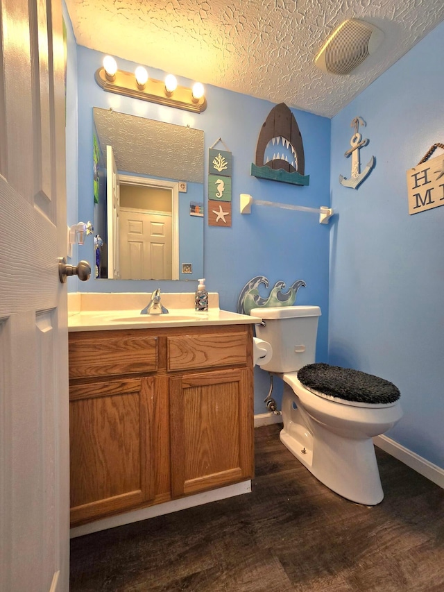 bathroom with toilet, hardwood / wood-style flooring, a textured ceiling, and vanity