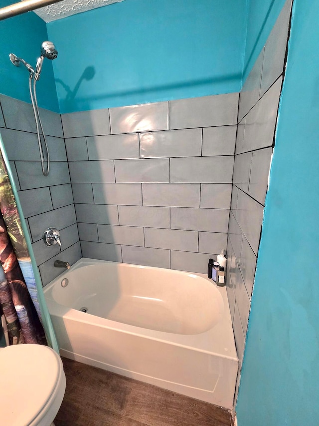 bathroom featuring toilet, shower / tub combo, and a textured ceiling