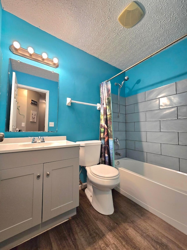 full bathroom with a textured ceiling, hardwood / wood-style floors, toilet, shower / bath combo, and vanity