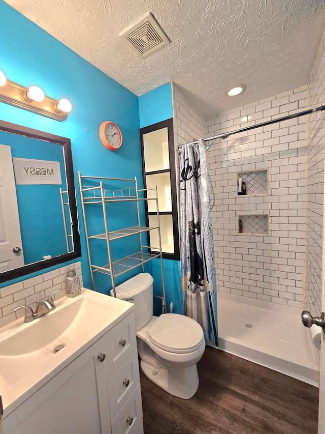 bathroom with a textured ceiling, walk in shower, hardwood / wood-style floors, and vanity