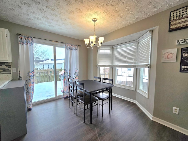 dining space with dark hardwood / wood-style flooring, a textured ceiling, a notable chandelier, and a wealth of natural light