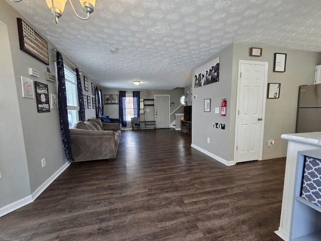 unfurnished living room featuring a textured ceiling, an inviting chandelier, and dark hardwood / wood-style floors