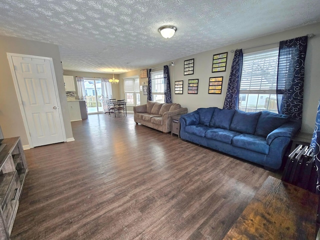 living room with dark wood-type flooring, a textured ceiling, and a notable chandelier