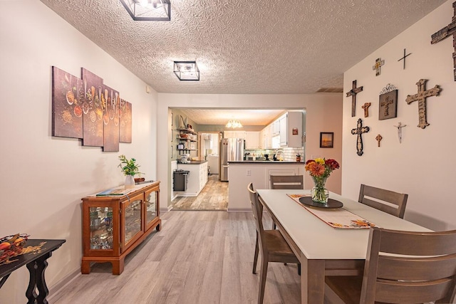 dining space with a textured ceiling and light hardwood / wood-style flooring