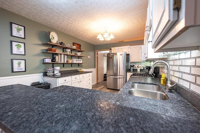 kitchen with sink, stainless steel fridge, a chandelier, and a textured ceiling