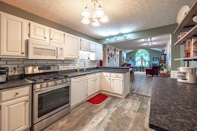 kitchen with white appliances, white cabinets, kitchen peninsula, and sink