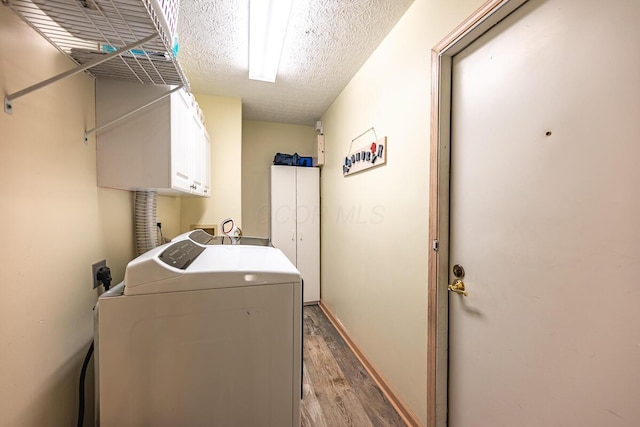 clothes washing area featuring a textured ceiling, light hardwood / wood-style flooring, cabinets, and separate washer and dryer