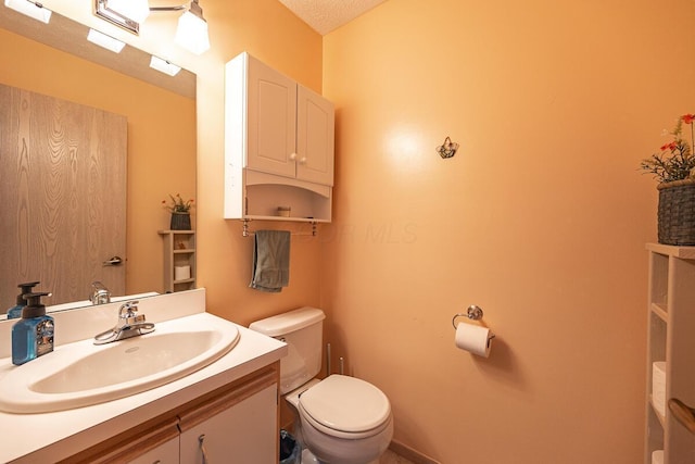 bathroom with toilet, vanity, and a textured ceiling