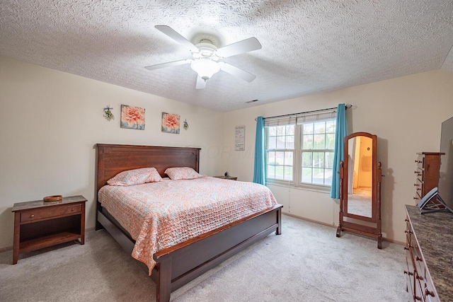 bedroom featuring light colored carpet, ceiling fan, and a textured ceiling