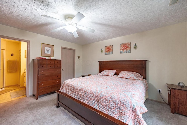 bedroom with light colored carpet, ceiling fan, a textured ceiling, and connected bathroom