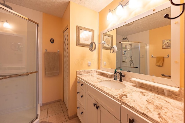 bathroom with tile patterned flooring, a shower with door, a textured ceiling, and vanity