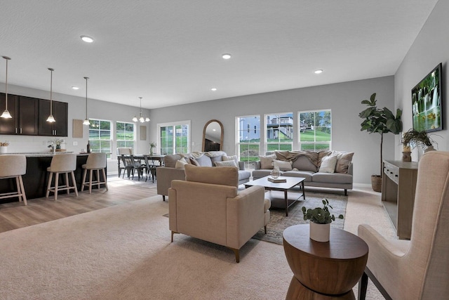 living room featuring light wood-style floors, recessed lighting, light colored carpet, and a notable chandelier