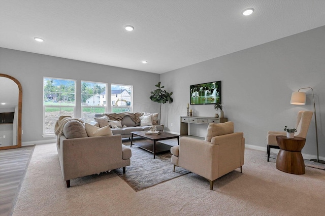 living area with baseboards, arched walkways, light colored carpet, a textured ceiling, and recessed lighting