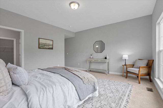 bedroom with baseboards, visible vents, and light colored carpet