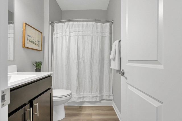 bathroom with curtained shower, vanity, toilet, and wood finished floors