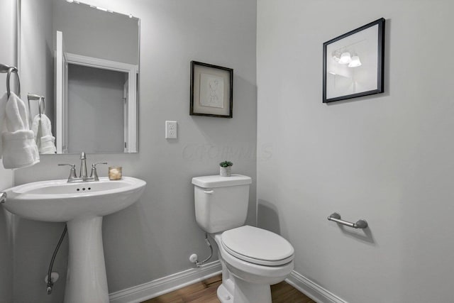 bathroom featuring toilet, baseboards, and wood finished floors