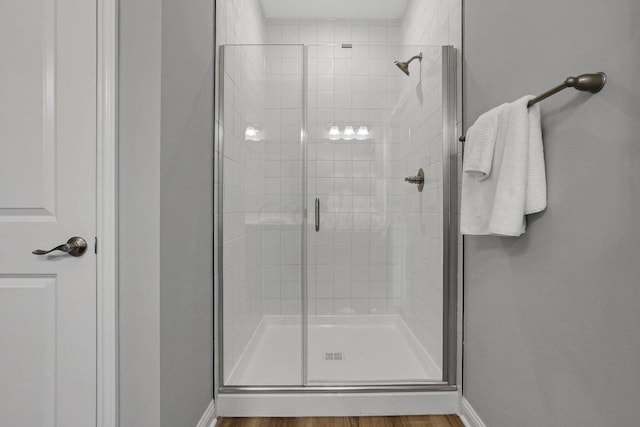 bathroom with a stall shower, baseboards, and wood finished floors