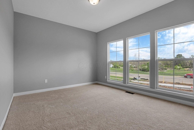 unfurnished room featuring visible vents, baseboards, and carpet flooring