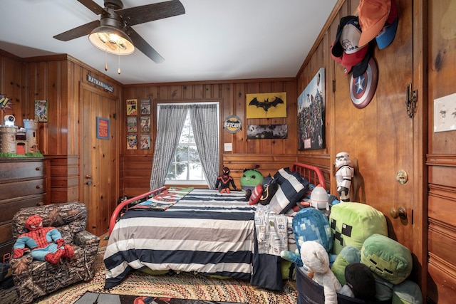 bedroom featuring ceiling fan, wooden walls, and crown molding