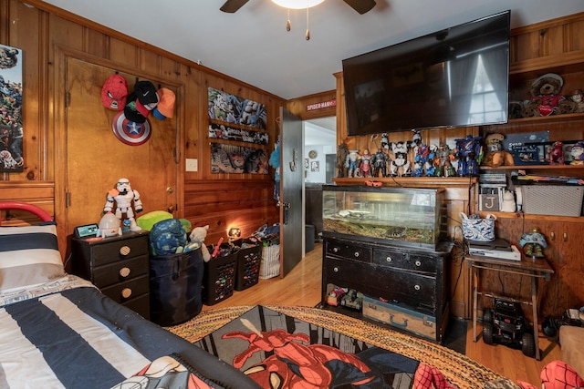 interior space with wooden walls, ceiling fan, and light wood-type flooring