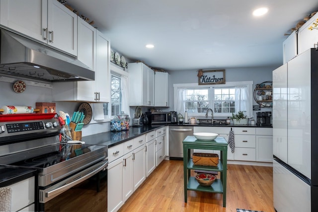 kitchen with appliances with stainless steel finishes, light hardwood / wood-style flooring, white cabinetry, and sink