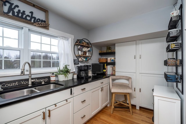 kitchen featuring white cabinets, light wood-type flooring, and sink