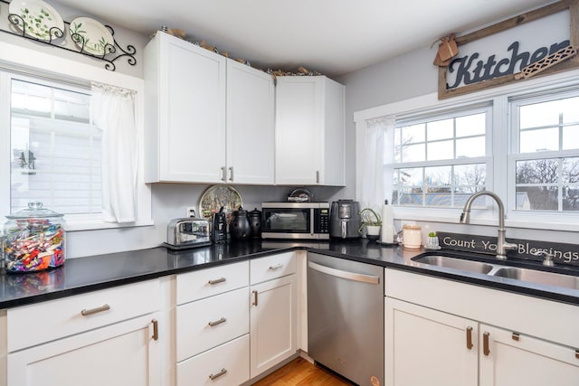 kitchen with appliances with stainless steel finishes, light hardwood / wood-style flooring, white cabinets, and sink