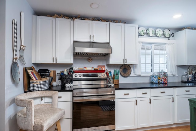 kitchen featuring stainless steel electric range oven, white cabinetry, and ventilation hood