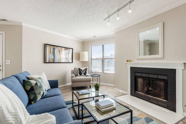 living room with a textured ceiling, hardwood / wood-style flooring, track lighting, and ornamental molding