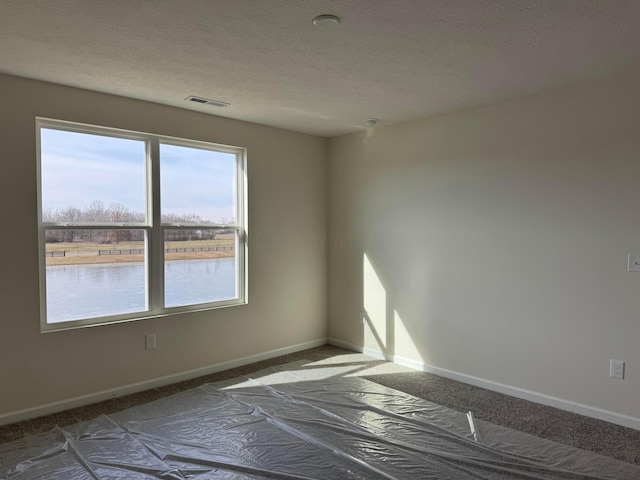 spare room featuring a water view and a textured ceiling