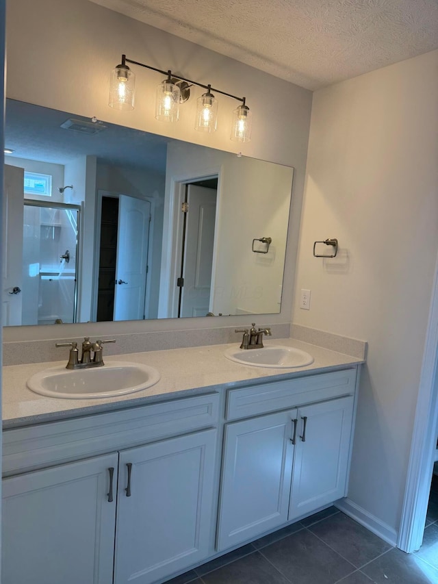 bathroom with walk in shower, vanity, tile patterned flooring, and a textured ceiling