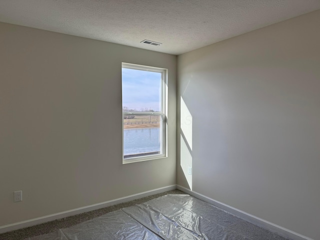 unfurnished room featuring a water view and a textured ceiling