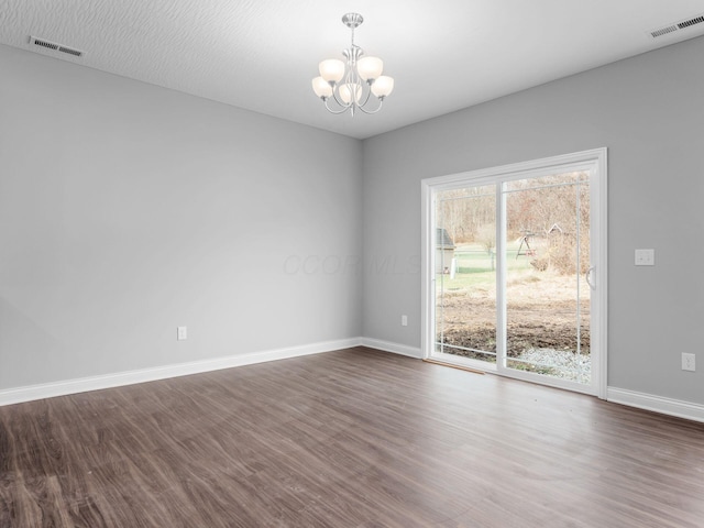 spare room featuring an inviting chandelier and dark wood-type flooring