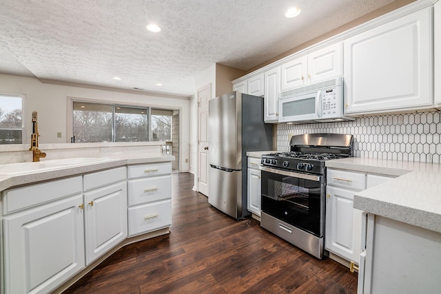 kitchen featuring stainless steel appliances, a textured ceiling, decorative backsplash, sink, and white cabinetry