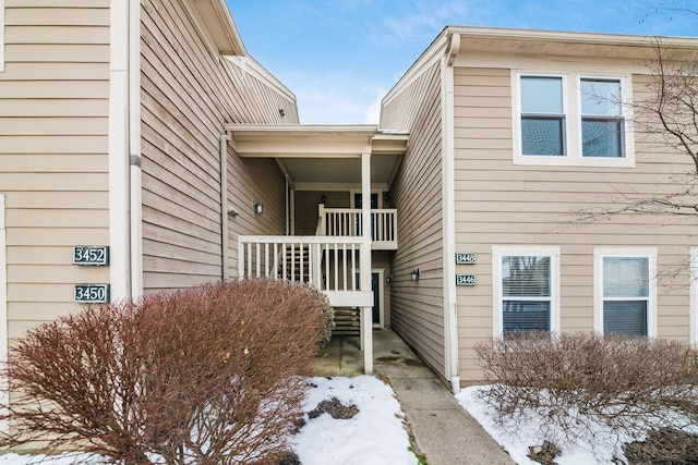 snow covered property entrance with a balcony