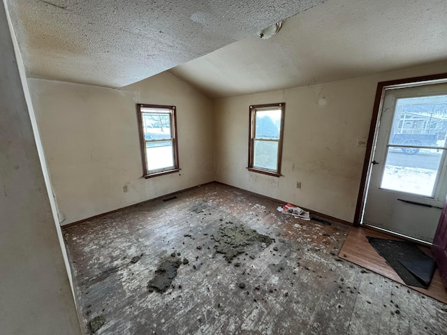 interior space featuring a textured ceiling and vaulted ceiling