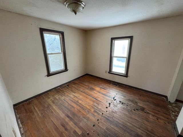 unfurnished room featuring dark hardwood / wood-style flooring and a textured ceiling